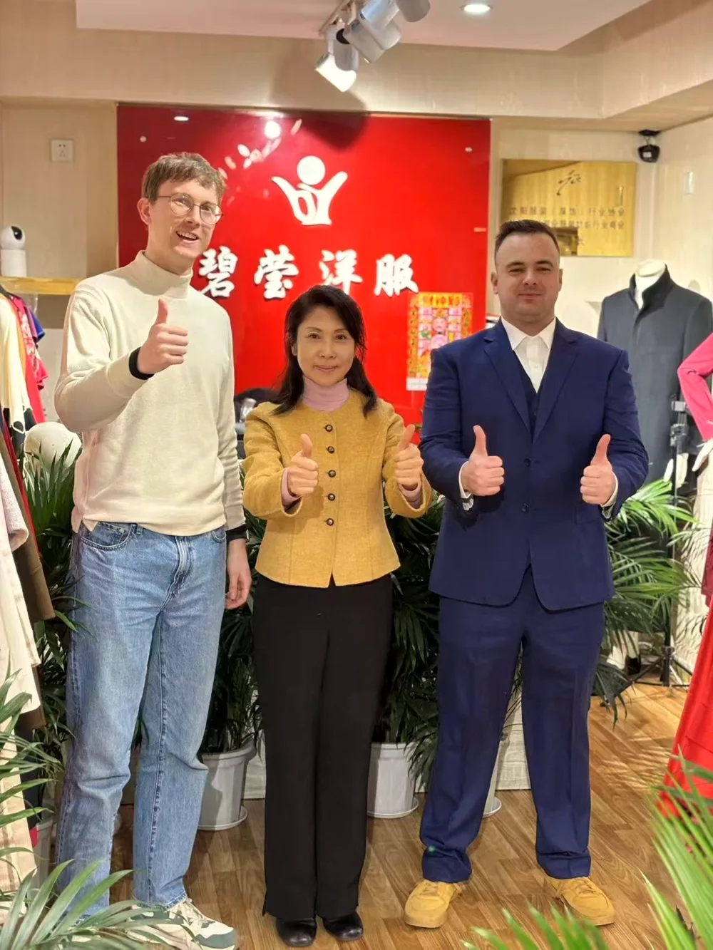 Biying with two clients in front of the shop sign wall